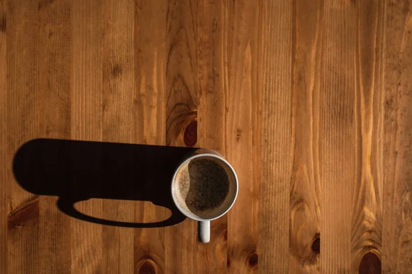 Ahşap bir masada kahve fincanının yüksek açılı görüntüsü