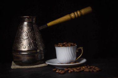 Kahve fincanında kahve çekirdekleri. Yakınlarda bir kahve makinesi var.