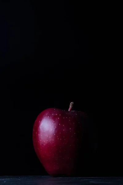 One red apple on a black background