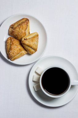 Şekerleme pişirme ve beyaz masa örtüsünün üzerinde bir fincan kahve. Çay takımı da beyaz.