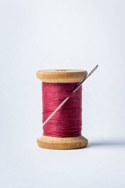 Beyaz arka planda iğne olan leylak rengi iplik makarası