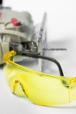 Beyaz arka planda sarı güvenlik gözlükleri. Arkasında bir yapboz yatıyor.