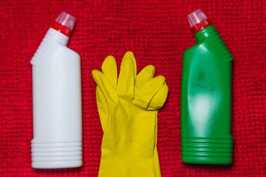 Temizlik konsepti Kırmızı halıda temizlik ürünleri ve sarı eldivenler var. Fotoğraf yukarıda.