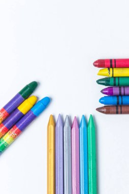 Beyaz arka planda üç sıra renkli kalem. Her kalem sırası merkeze doğru yönelir. Fotoğraf üstte.