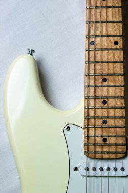 Beyaz arka planda beyaz elektro gitar. Fotoğrafta boyun ve gitar destesi var..
