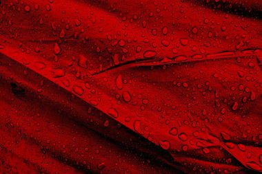 Kumaşın üzerine su damlaları. Kırmızı arka planda su damlaları. Yoğunlaş. Su damlaları arka plan. 