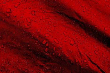 Kumaşın üzerine su damlaları. Kırmızı arka planda su damlaları. Yoğunlaş. Su damlaları arka plan. 