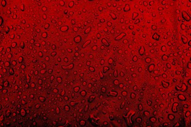 Kumaşın üzerine su damlaları. Kırmızı arka planda su damlaları. Yoğunlaş. Su damlaları arka plan. 