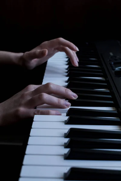 hands play the piano. black piano. white and black keys