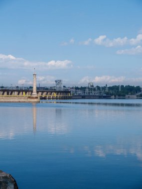 Nehir iskelesi. Mavi su. Nehir rıhtımında yaz günü. Gökyüzündeki bulutlar nehire yansıyor..