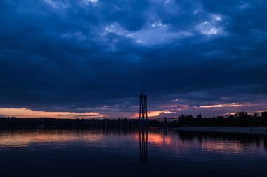 Bitmemiş köprü. Nehrin üzerinde gün batımı. Günbatımı arka planında bir köprü. bulutlu gökyüzü.