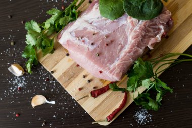 Yeşiller, baharatlar ve et kesme tahtasında. Bir parça domuz eti, biber, sarımsak, tuz. Evde yemek pişir. taze yiyecek