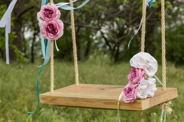 wedding place. swing for the bride. wedding wedding concept. pink and white flowers. green grass, wooden swing.