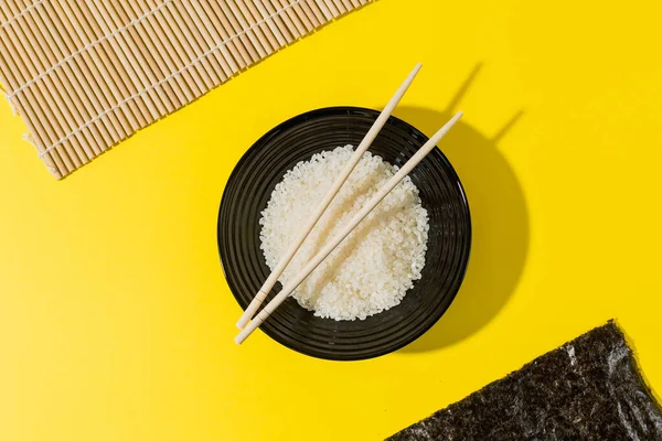 Rijst Voor Sushi Een Zwarte Plaat Een Gele Achtergrond Nori — Stockfoto