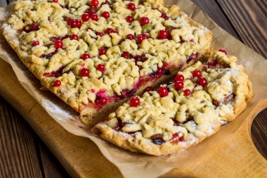 Lezzetli bir kahvaltı. Aşçı pastaya şeker serpiyor. Tahtada böğürtlenli ev yapımı rendelenmiş turta. Büyük bir dilim pasta. Hibiscus şeffaf bir bardakta içer..