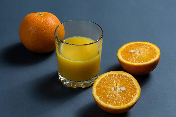 Orange juice and sliced orange. a glass of orange juice, a whole orange and a sliced orange on the table.