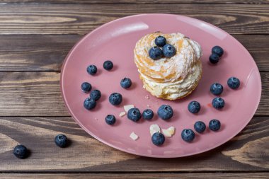 Pembe tabakta yabanmersinli kremalı pasta. Düğün hediyesi. Yabanmersinleri masaya saçılmış..
