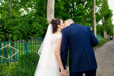 Güzel gelin ve damat öpüşme açık havada düğün gününde kucaklayan.