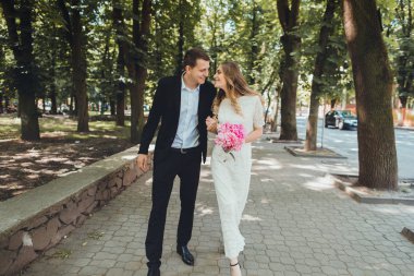 Gelin ve damat gün açık havada yürüyüş düğününde Doğa bahar. Gelin çift, mutlu yeni evli kadın adam yeşil park kucaklayan. Açık sevgi dolu.