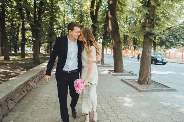 Bruden och brudgummen på bröllop dag promenader utomhus på vår natur. Brudparet, lycklig nygift kvinna man omfamnar i grön park. Kärleksfull utomhus. — Stockfoto