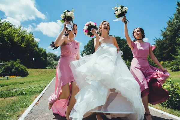 Glückliche Braut mit Brautjungfern am Hochzeitstag im Park — Stockfoto