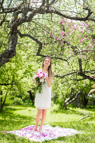 Zachte gelukkig brunette vrouw met boeket van pioenrozen in tussen de bomen een zonnige dag — Stockfoto