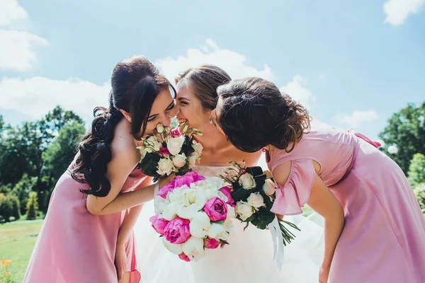 Glückliche Braut mit Brautjungfern am Hochzeitstag im Park Stockfoto