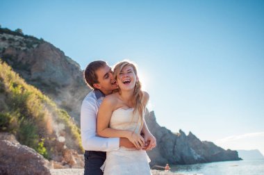 Romantik Çift sahilde eğleniyor. Sevgi, çekici bir adam ve kadının akşam gün batımını izlemek, tutuşup genç