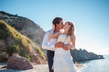 Romantik Çift sahilde eğleniyor. Sevgi, çekici bir adam ve kadının akşam gün batımını izlemek, tutuşup genç