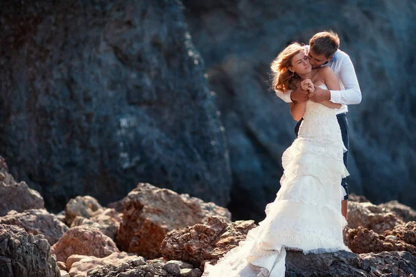 Liebliches Hochzeitspaar, das sich sanft umarmt. schöne Berglandschaft im Hintergrund Stockbild