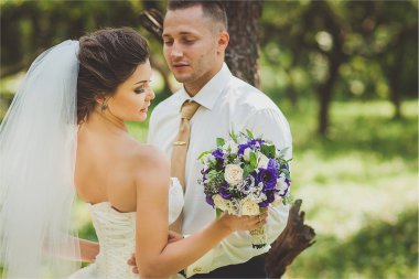 Gelin ve damat bir park kissing.couple yeni evliler doğa yeşil orman düğünde fotoğraf portre vardır.