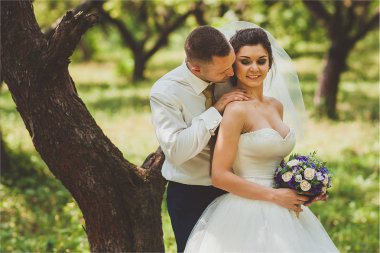 Gelin ve damat bir park kissing.couple yeni evliler doğa yeşil orman düğünde fotoğraf portre vardır.