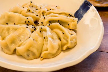 El yapımı Çin mantısı Jiaozi, siyah susam tohumlarıyla seramik tabakta güzel bir daire şeklinde dizilmiş.