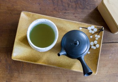 Seramik orkide tabağında küçük siyah çaydanlık ve ahşap masa ile küçük beyaz seramik çay fincanı. Yeşil çay için gerçek Çin çayı kültürü. Gongfucha töreni..