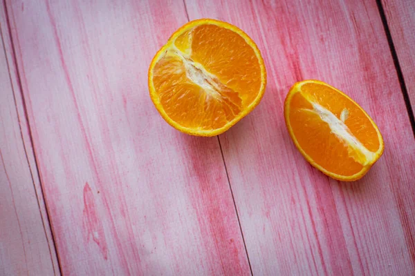 two halves of an orange on a pink background