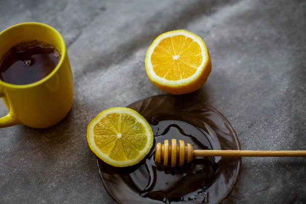black tea with honey, lemon on a gray background