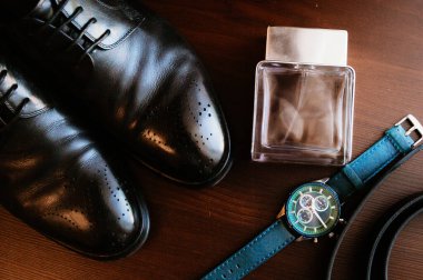 Masadaki erkek aksesuarları: ayakkabılar, saatler, kemer ve parfüm