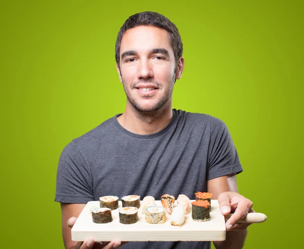 Young man eating sushi on green background
