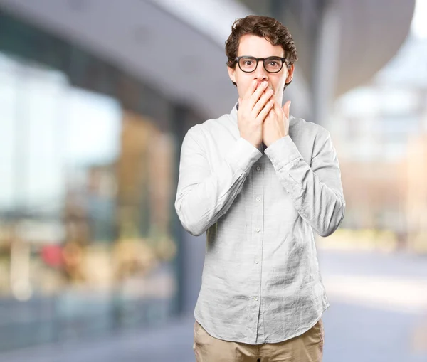 Astonished young man covering his mouth