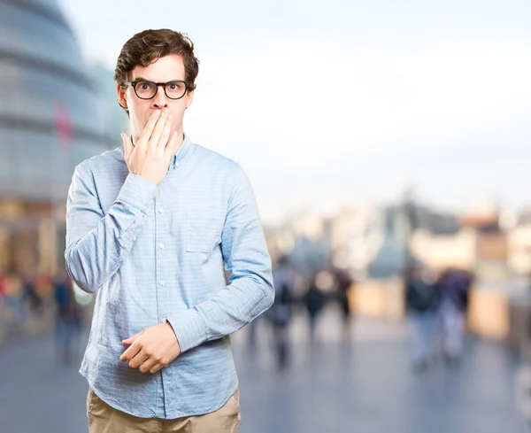 Astonished young man covering his mouth