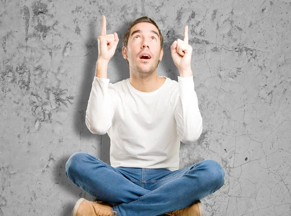 Seated young man pointing up