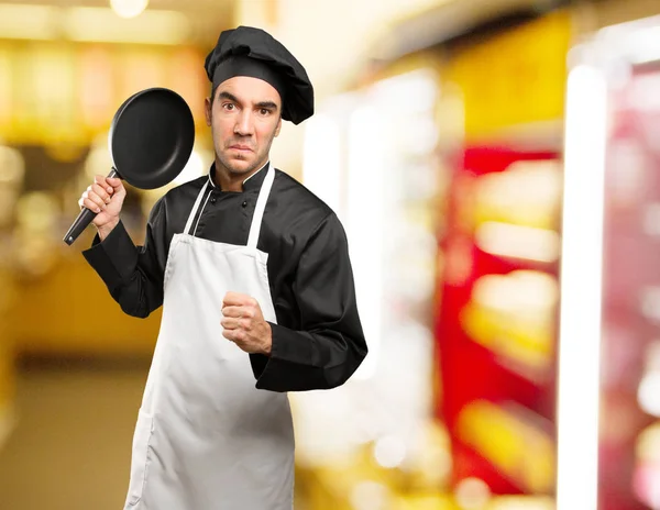 Angry young chef using a cooking utensil