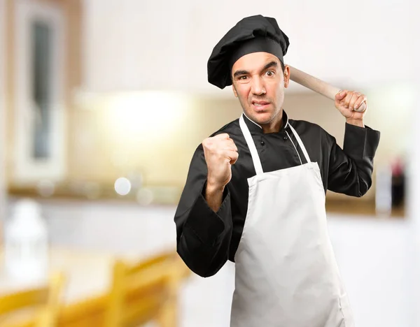 Angry young chef using a cooking utensil