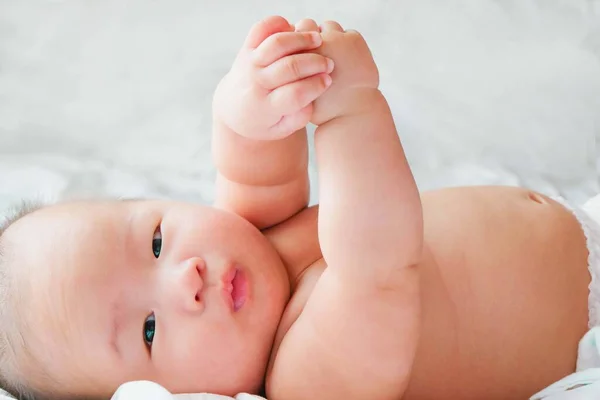 Portrait of a newborn Asian baby on the bed , Charming black-eyed baby 4 month old lies in bed,A child resting on a bed and looking