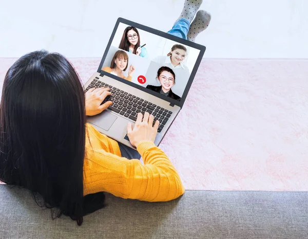 İş kadınlarının iş hakkında konuştuğu dizüstü bilgisayar ekranı görüntüsü, kanepenin yanında oturmak, video görüşmesi yapmak, evden çalışan video konferans uygulamasını kullanarak Corona virüsünü önlemek için kullanmak.