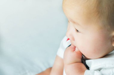 Yeni doğmuş Asyalı bir bebeğin portresi. Yatağa mavi bebek tulumu giydi. Yakışıklı bebek. 5 aylık bebek bir bebekle yatakta uzanıyor.