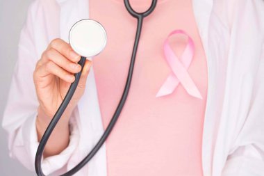 Dünya Göğüs Kanseri Günü Konsepti, sağlık hizmetleri - Pembe kurdele, steteskop, göğüs kanseri farkındalığı için kırmızı kalp, sembolik yay rengi kadın meme tümörü olan insanlar üzerinde farkındalık yaratıyor.
