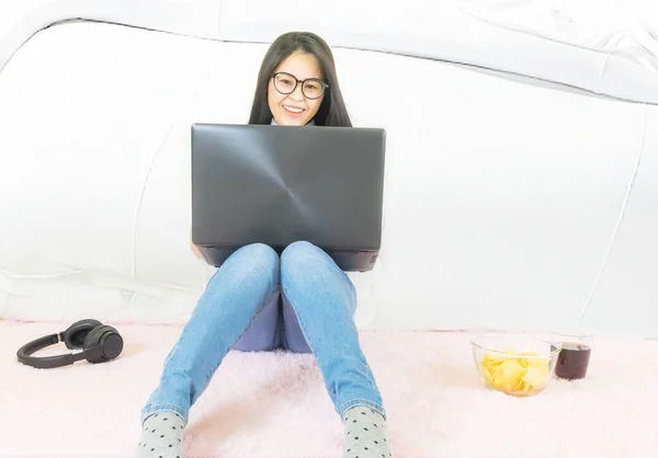 soft selective focus Young beautiful asian woman wore gray t shirt and jean,sitting on pink carpet in living room,work online lifestyle,relax at home with coffee mug,home working laptop,work from home
