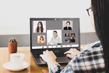 Laptop ekran görüntüsü, Asyalı bir kadının işten bahsetmesi, çalışma masasında oturması, video konferans uygulamasını evden uzak tutup Corona virüsünü önlemek için uzaktan iletişim kurmasını sağlıyor.