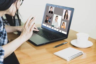 Laptop ekran görüntüsü, Asyalı bir kadının işten bahsetmesi, çalışma masasında oturması, video konferans uygulamasını evden uzak tutup Corona virüsünü önlemek için uzaktan iletişim kurmasını sağlıyor.
